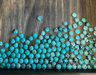 Turquoise cabochons scattered on a wooden tray